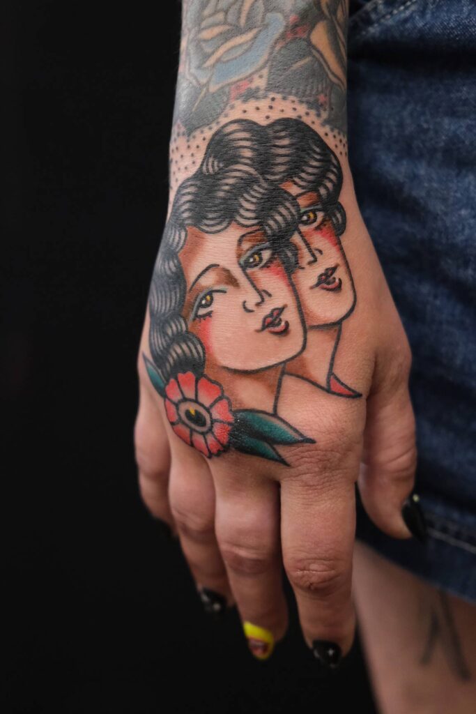 Oldschool Tattoo auf dem Handrücken mit zwei Frauenköpfen im klassischen Stil – Symbol für das Sternzeichen Zwilling, gestochen bei Good Old Times Tattoo in Berlin Mitte.