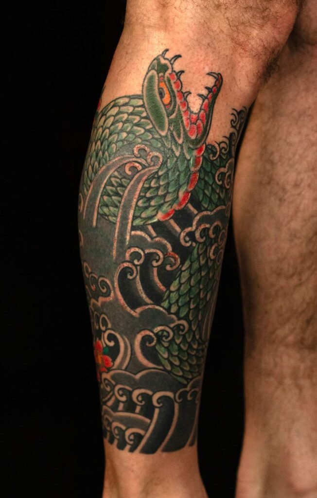 Japanisches Schlangentattoo (Irezumi) am Bein mit Wellenmotiv in traditioneller Komposition